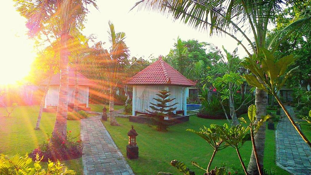 a small house in a garden with a grass yard at D'Mell Bali in Nusa Dua