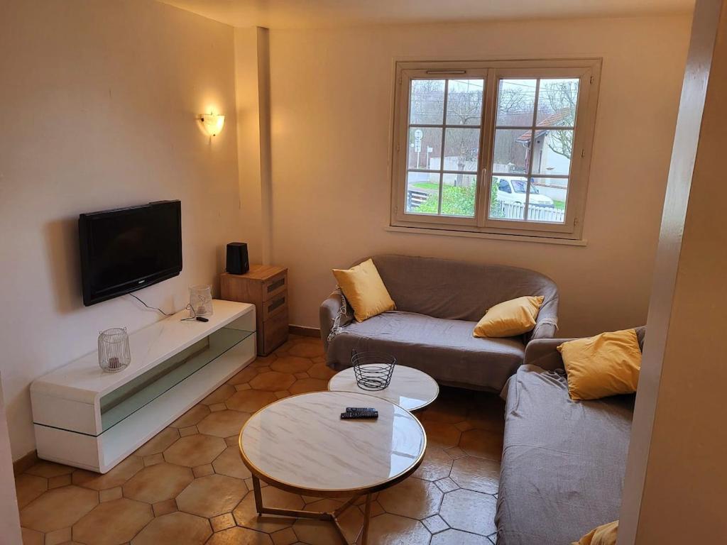 un salon avec un canapé et une table dans l'établissement Grand pavillon avec jardin, à Tremblay-en-France