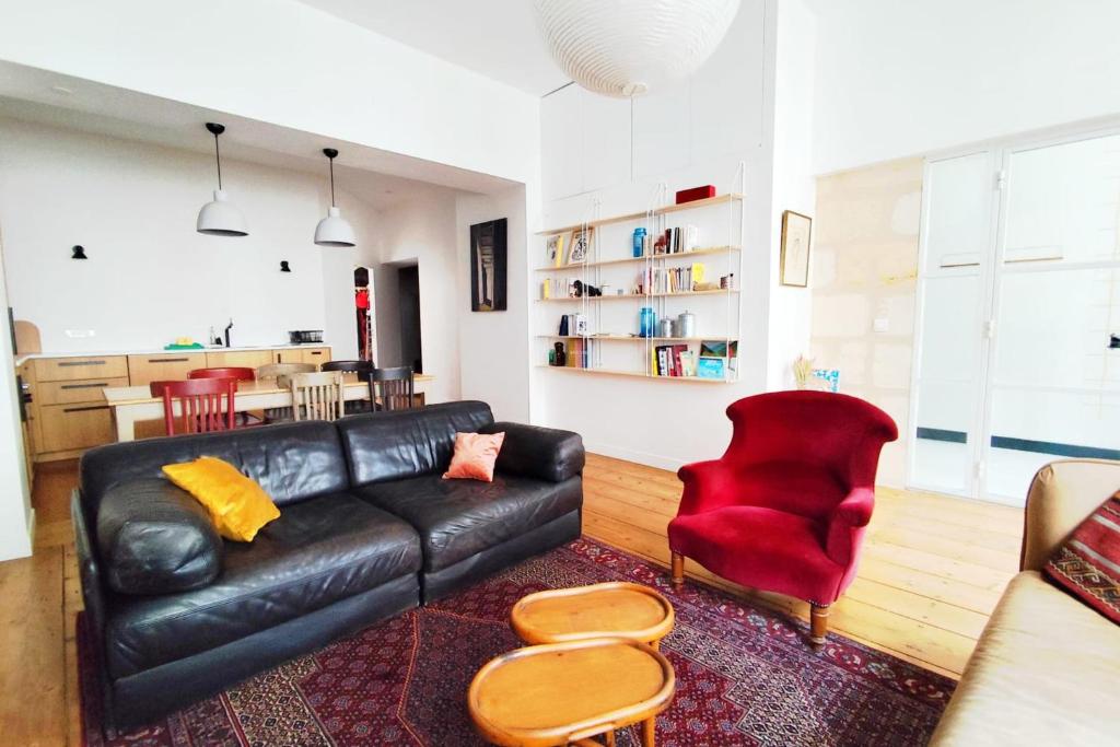 - un salon avec un canapé en cuir noir et un fauteuil rouge dans l'établissement Beautiful T3 in the historic heart of Bordeaux, à Bordeaux