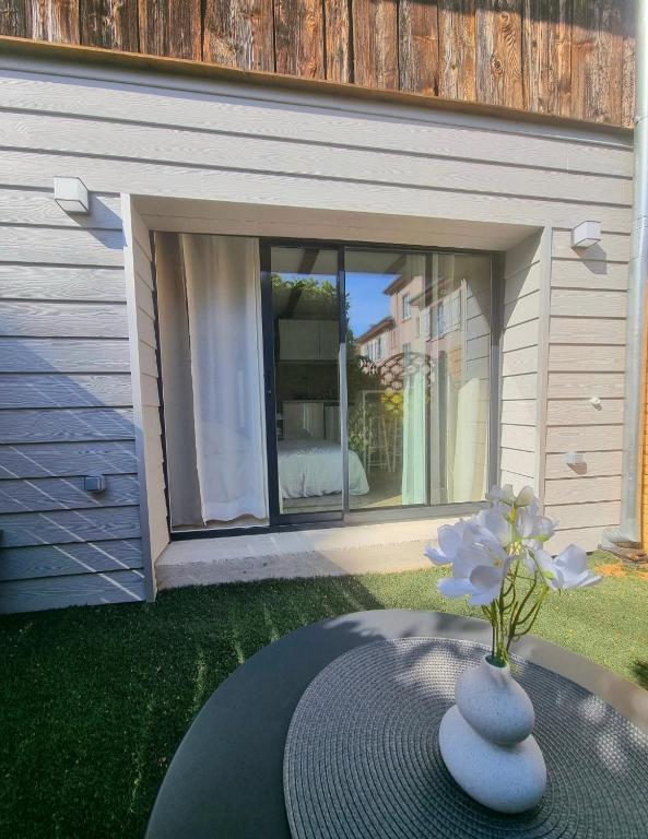 un vase avec une fleur sur une table dans une cour dans l'établissement Suite cosy indépendante Evasion env Colmar, à Wintzenheim