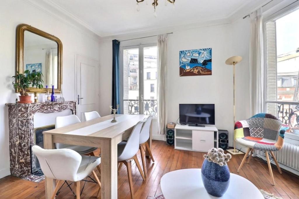 un salon avec une table, des chaises et une télévision dans l'établissement Nice haussmannian apartment in Paris, à Paris