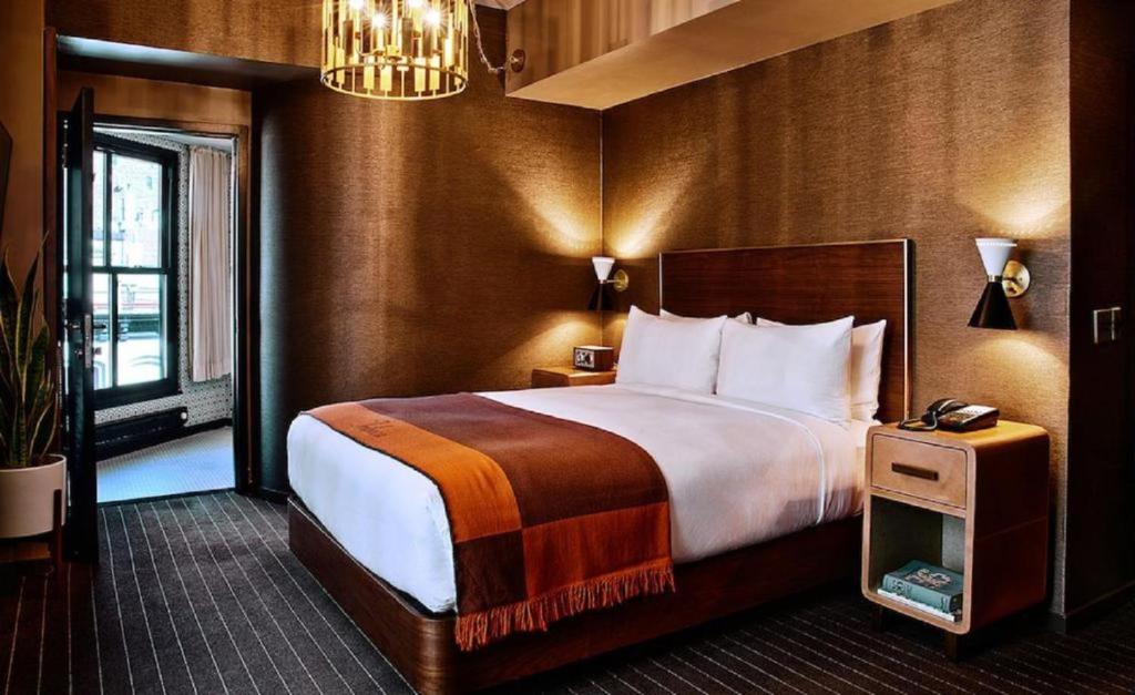 una camera d'albergo con un grande letto e un lampadario a braccio di Hotel AELA SUITES Near IGI Airport By GROSS GROUP a Nuova Delhi