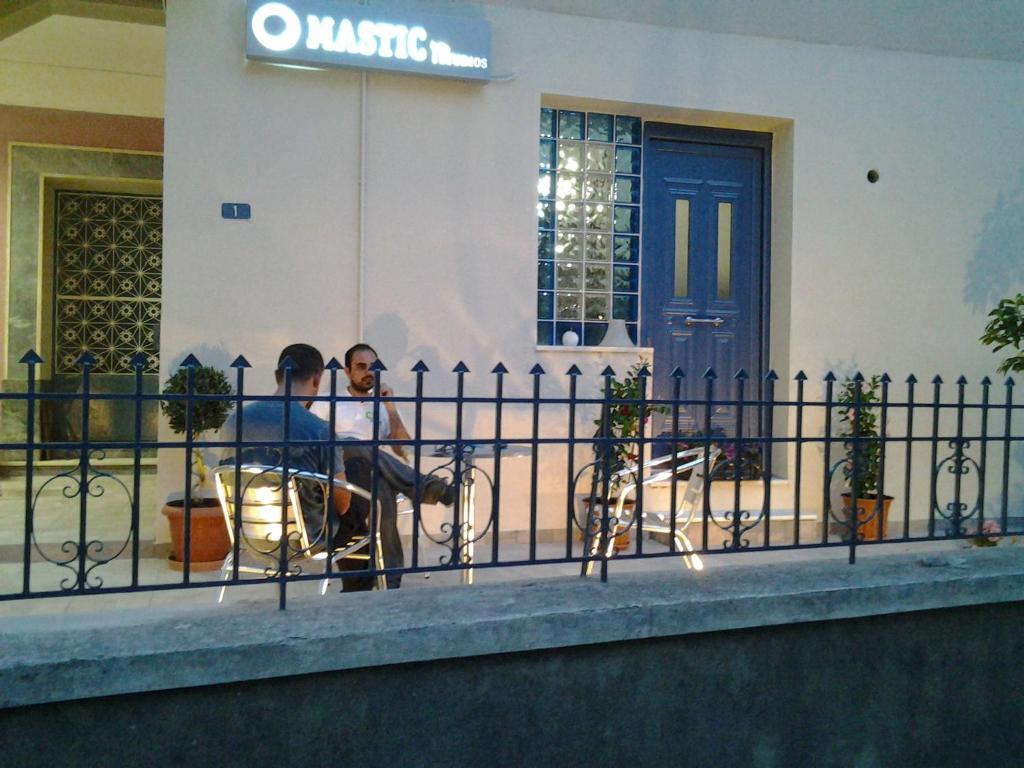 un hombre sentado en una boca de incendios junto a una valla en Mastic Point Studios, en Chios