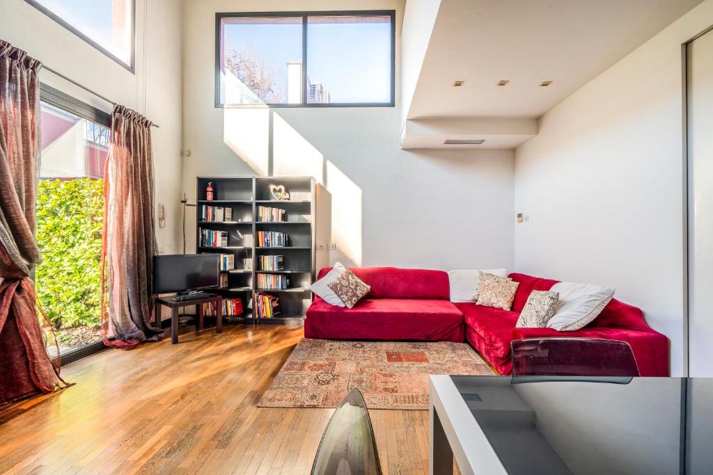 un soggiorno con divano rosso e finestra di RED LOFTY Milano- Loft moderno comodo per Ippodromo, San Siro, Rho Fiera-MiCo e Politecnico, parking a Milano