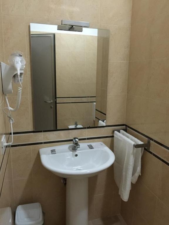 um banheiro com uma pia e um espelho em Herges Hotel em Durrës