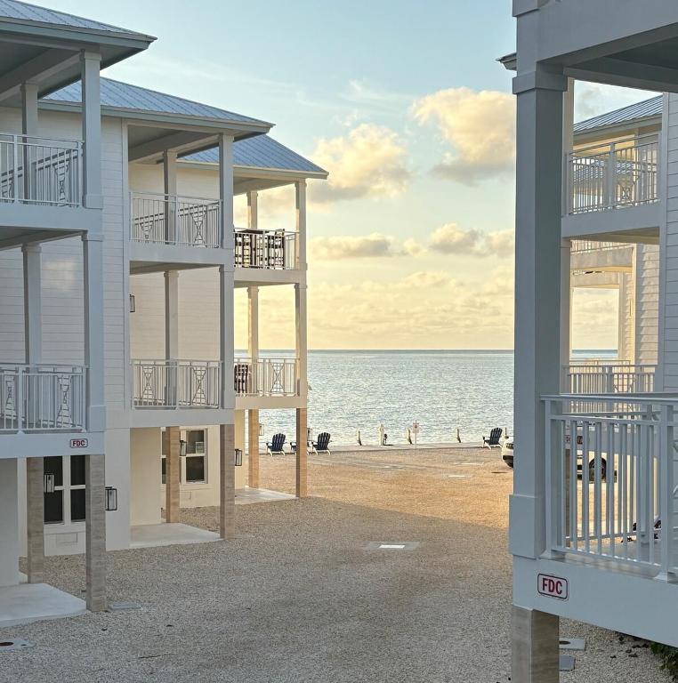 a building on the beach with the ocean in the background at Hooked on Islamorada Oceanfront Townhome, Private Dock, Pool in Islamorada