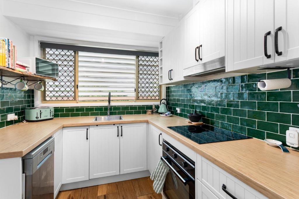 a kitchen with white cabinets and green tiles at Seaside Serenity: Charming 2-Bedroom Getaway in Scarborough