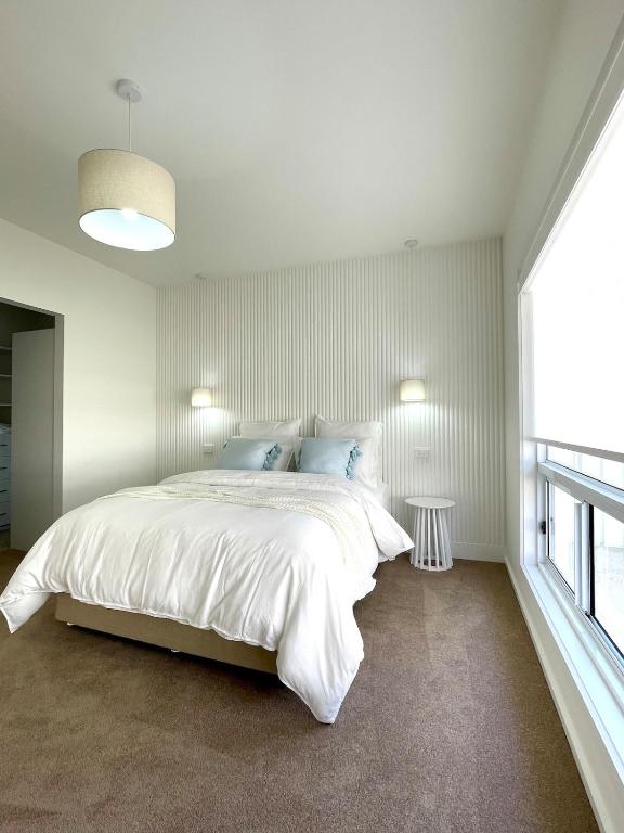 a white bedroom with a large bed and a window at Straun Street House in Naracoorte