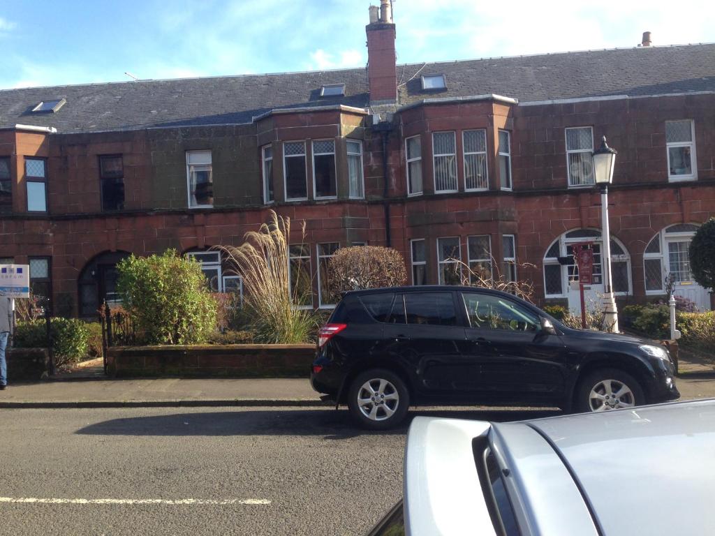 un coche negro estacionado frente a un edificio de ladrillo en Charles's Street, en Largs