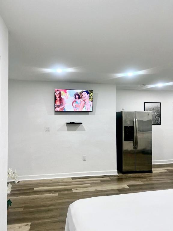 a tv on a wall in a room with a refrigerator at Beautiful studio with private backyard in Abbeyville