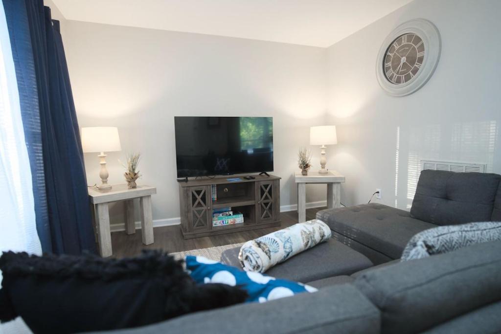 un salon avec un canapé et une télévision à écran plat dans l'établissement Modern Two BR Townhome, Workspace, Free Parking and Wi-Fi, à Raleigh