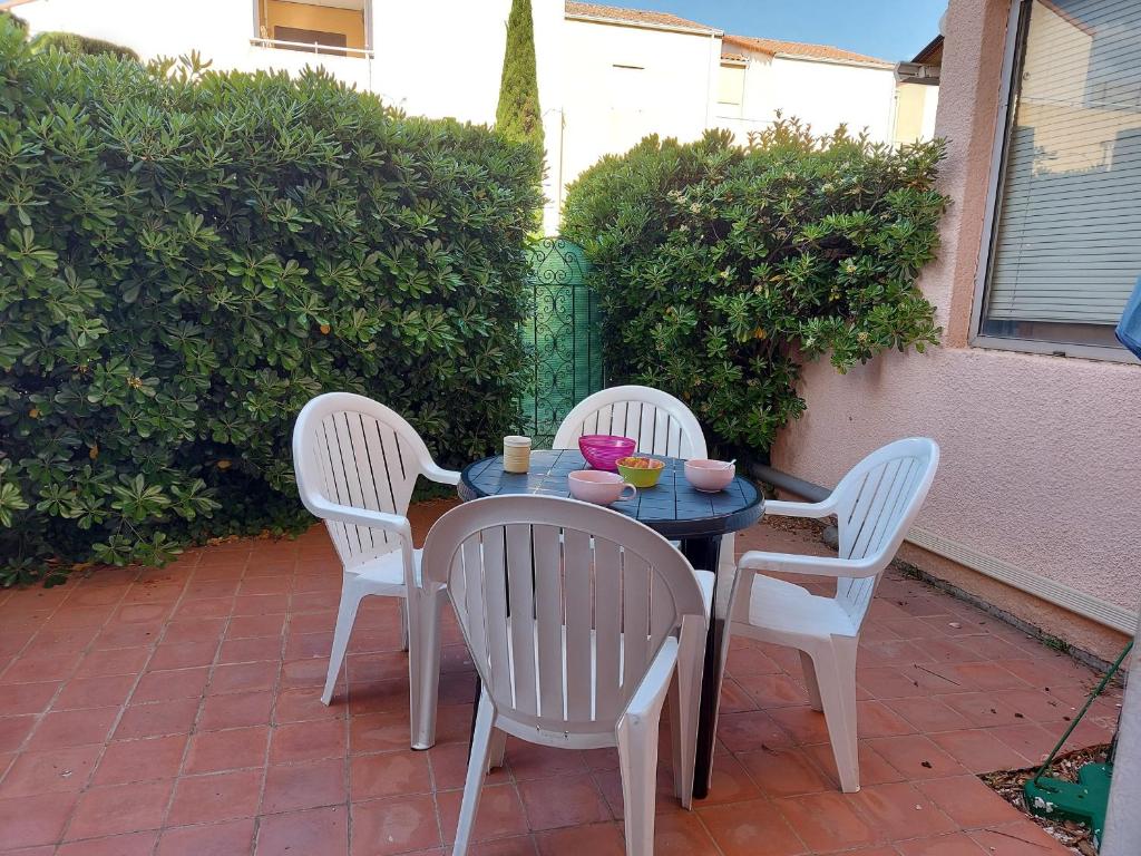 trois chaises et une table avec des boissons dessus sur une terrasse dans l'établissement Appartement 4 pers avec terrasse, piscine et parking sécurisé - FR-1-776-137, à Argelès-sur-Mer