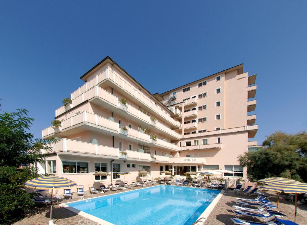 un hotel con piscina, sillas y un edificio en Hotel Man en Lido di Savio