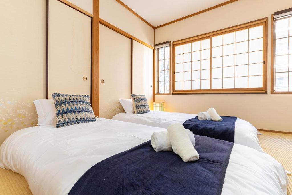 zwei Betten in einem Zimmer mit zwei Fenstern in der Unterkunft Cozy condo for 2 PPL near Teradacho Sta 4 min walk cecilia301 in Osaka