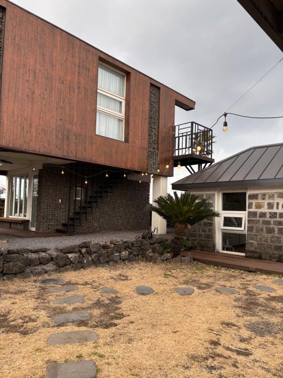a house with a stone yard in front of it at Kimnung House Anmok in Jeju