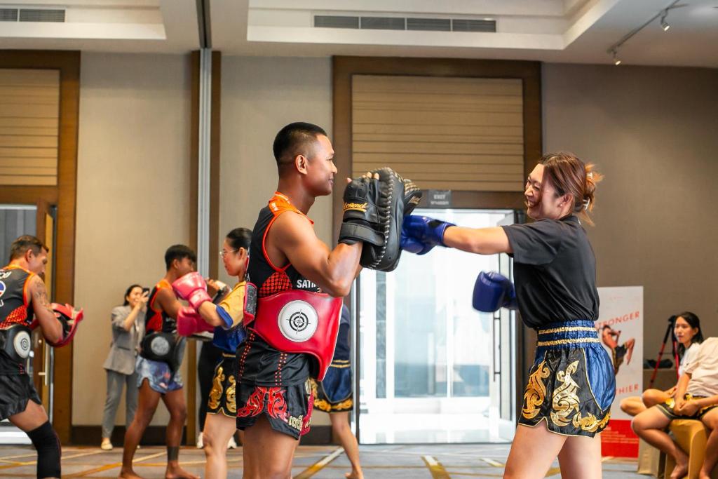 A Muay Thai training session is taking place in a bright hotel fitness space.