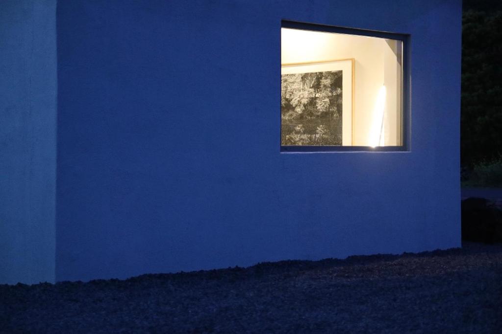 a window in a blue wall with a picture at Empty Room Jeju in Jeju