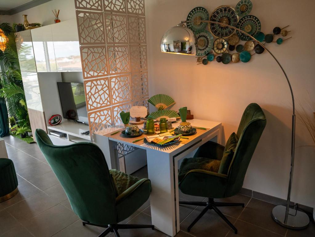 a room with a table with green chairs and a lamp at Appartement de L'Espiguette in Le Grau-du-Roi