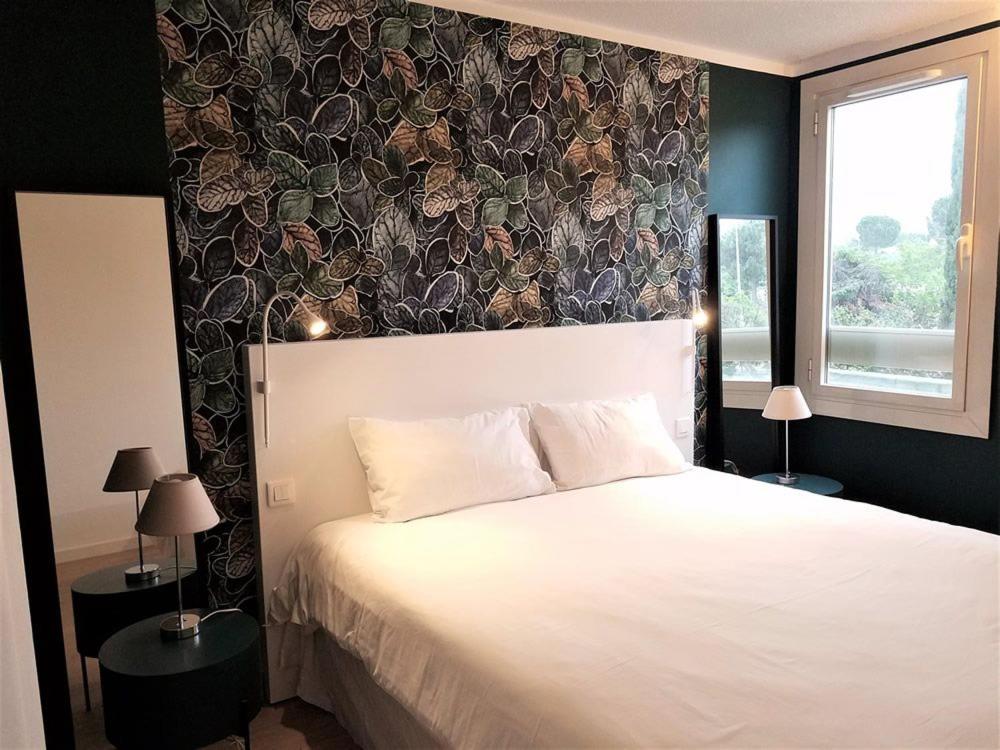 a bedroom with a white bed and a black wall at Brit Hotel Marseille Aéroport in Les-Pennes-Mirabeau