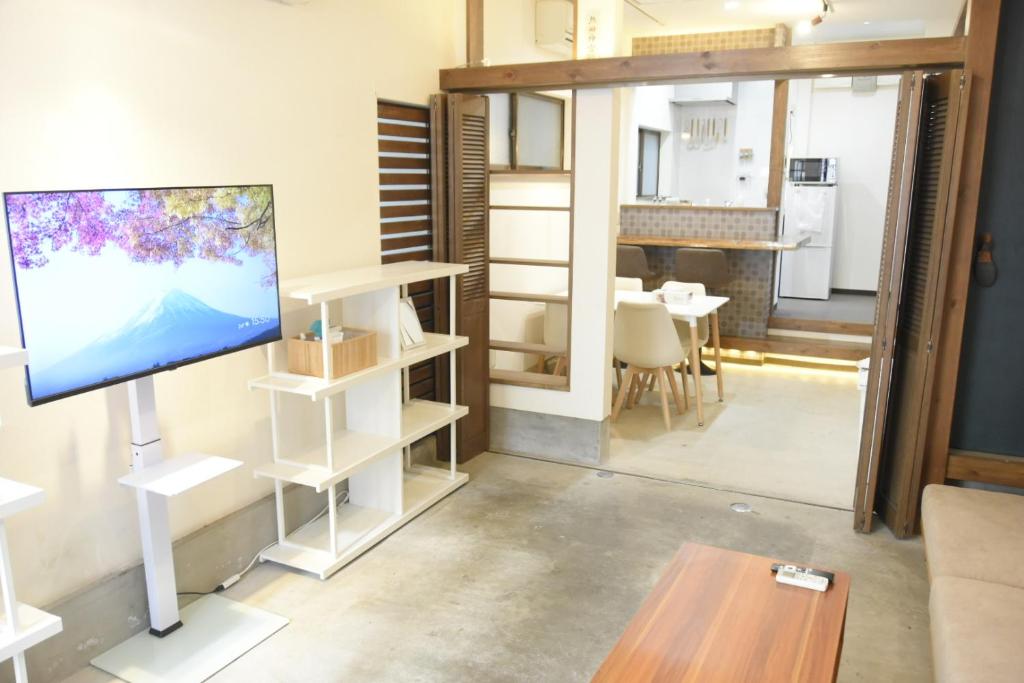 Una sala de estar con un televisor de pantalla plana y una mesa. en Asakusa Sky House, en Tokio
