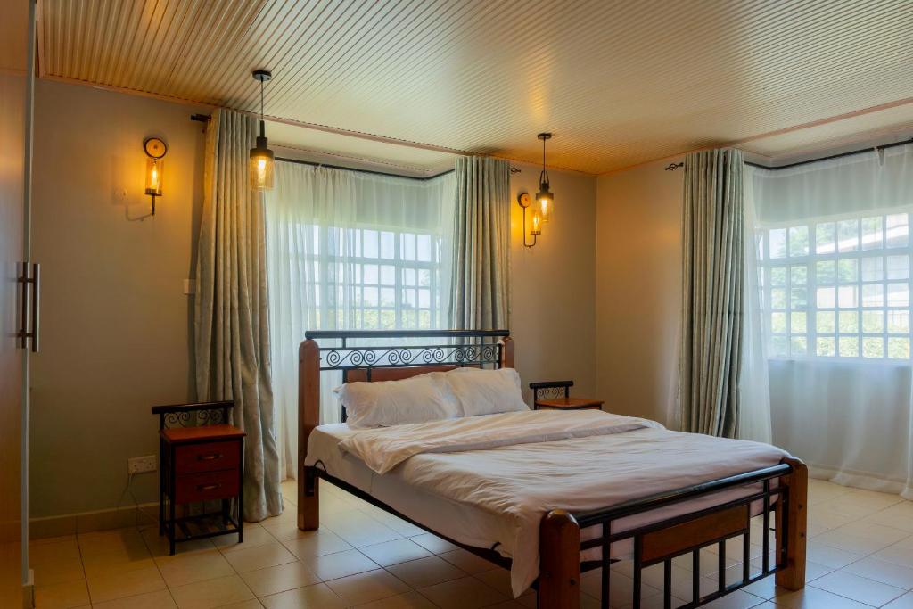 a bedroom with a bed and two windows at Gatundu Slow Life Farm Stay and Hiking in Tea Farms in Kangunyi