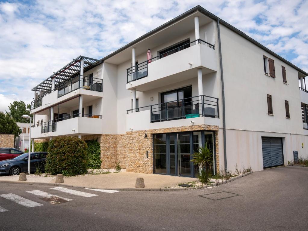 a white apartment building with a parking lot at Appartement de L'Espiguette in Le Grau-du-Roi
