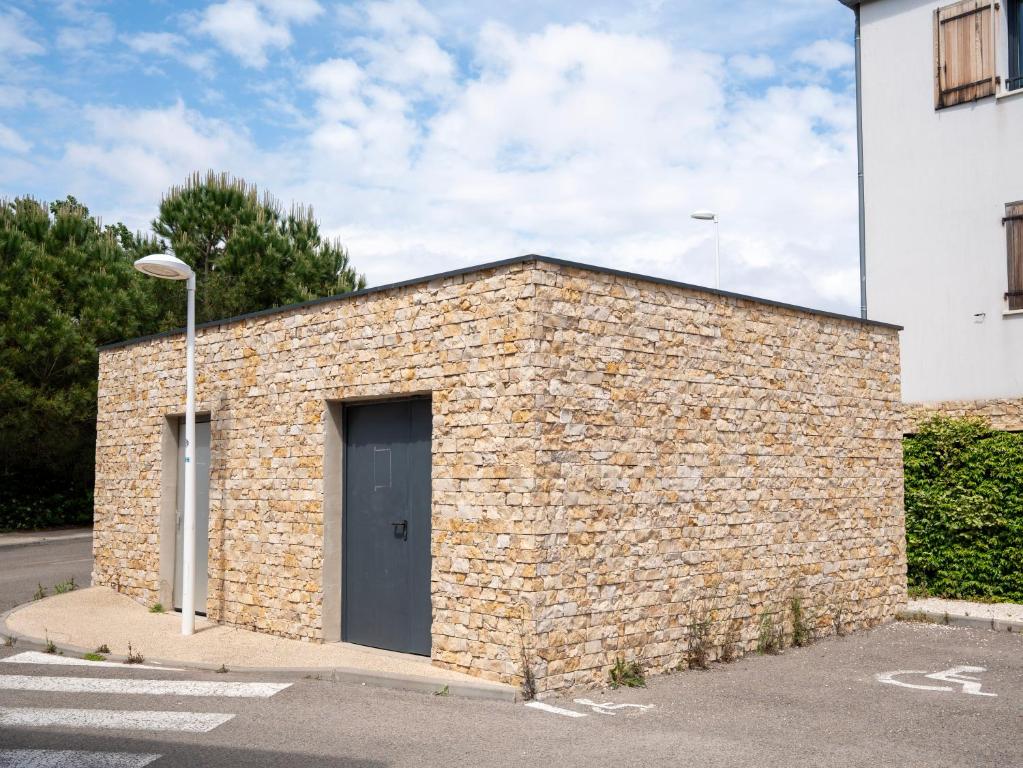 a brick building with a black door on a street at Appartement de L'Espiguette in Le Grau-du-Roi