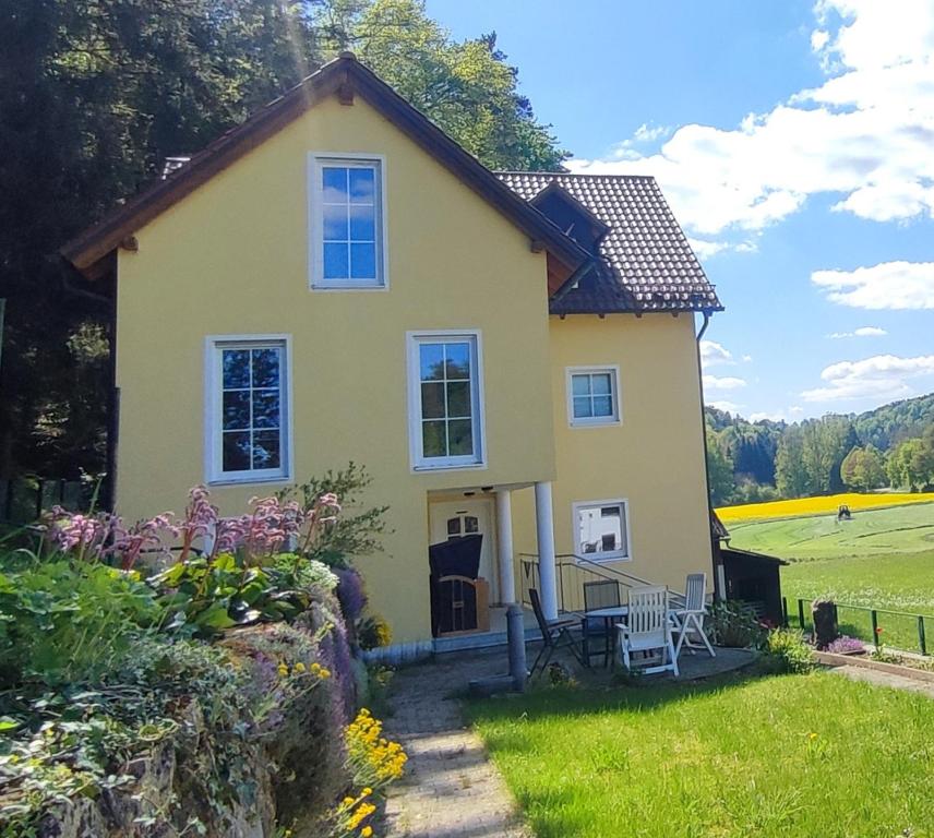 a small yellow house with a lawn at Ferienhaus am Bach mit großem Garten in Deuerling