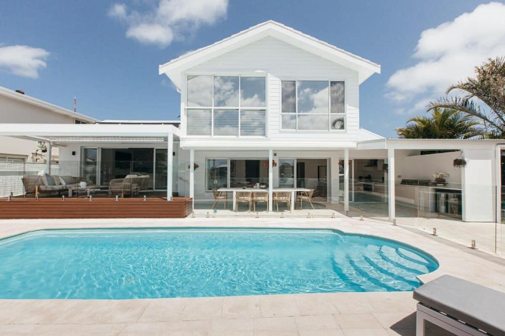 a house with a swimming pool in front of a house at MainSail by Coast Hosting in Daleys Point