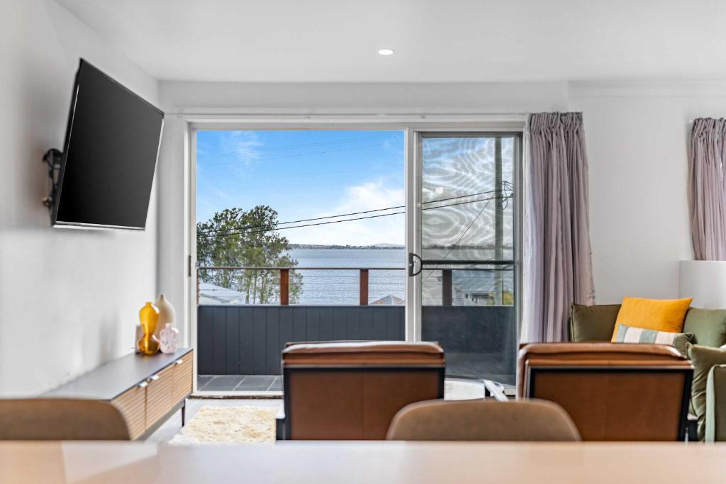 a living room with a large window and a couch at Retro Lake Vista By Coast Hosting in Budgewoi