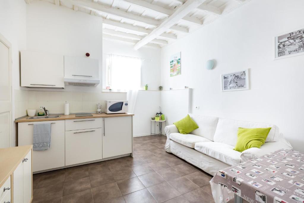 ローマにあるGuest Apartment Montiの白いリビングルーム(ソファ付)、キッチンが備わります。