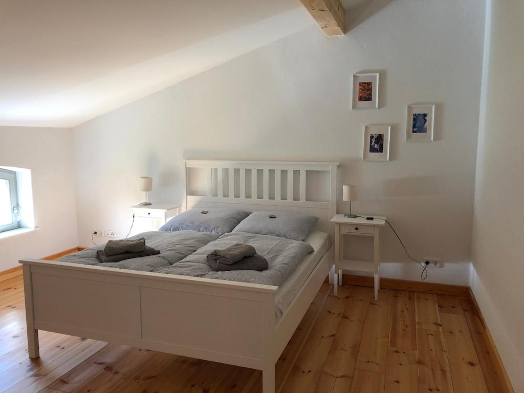 a bedroom with a white bed and a wooden floor at Ferienwohnung Alte Schmiede mit Gutspark in Rambin