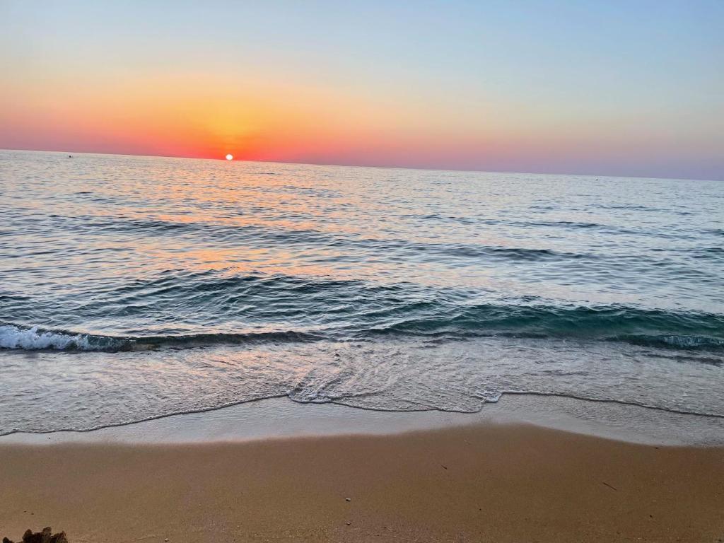 einen Sonnenuntergang am Strand mit dem Meer in der Unterkunft Casa Margot Costa Verde Sardinia in Torre Dei Corsari