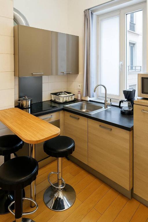 - une cuisine avec un évier et une table avec des tabourets de bar dans l'établissement Opera - Chatelet, à Paris