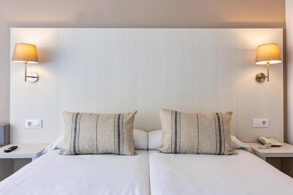 a bedroom with a white bed with two pillows at Minura Sur Menorca in Punta Prima