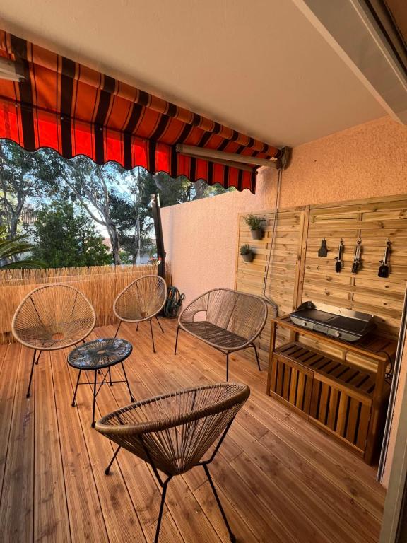 a patio with chairs and tables on a wooden deck at Confort et évasion à l'Almanarre in Hyères
