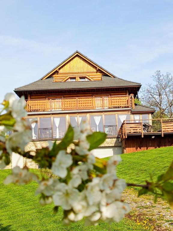 Una gran casa de madera con flores blancas delante de ella. en Dom Na Rozceściu, en Koniaków