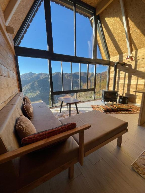 a room with a large window with a couch and a fireplace at Nozona Villa-Dağ Evleri in Çamlıhemşin