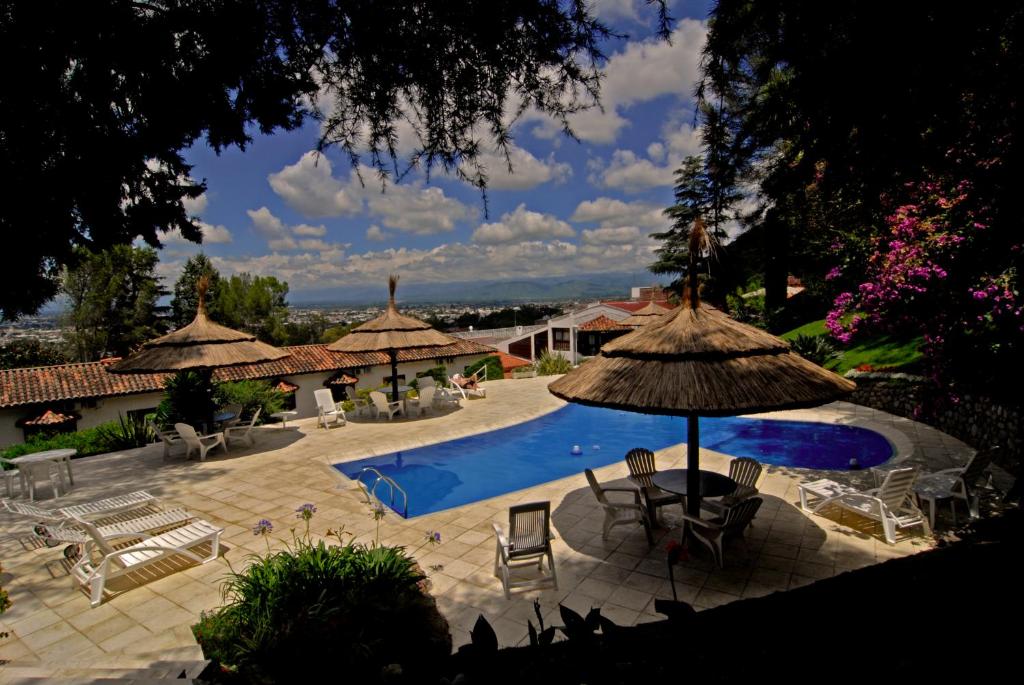 una piscina con sombrillas y sillas en Portezuelo Hotel en Salta