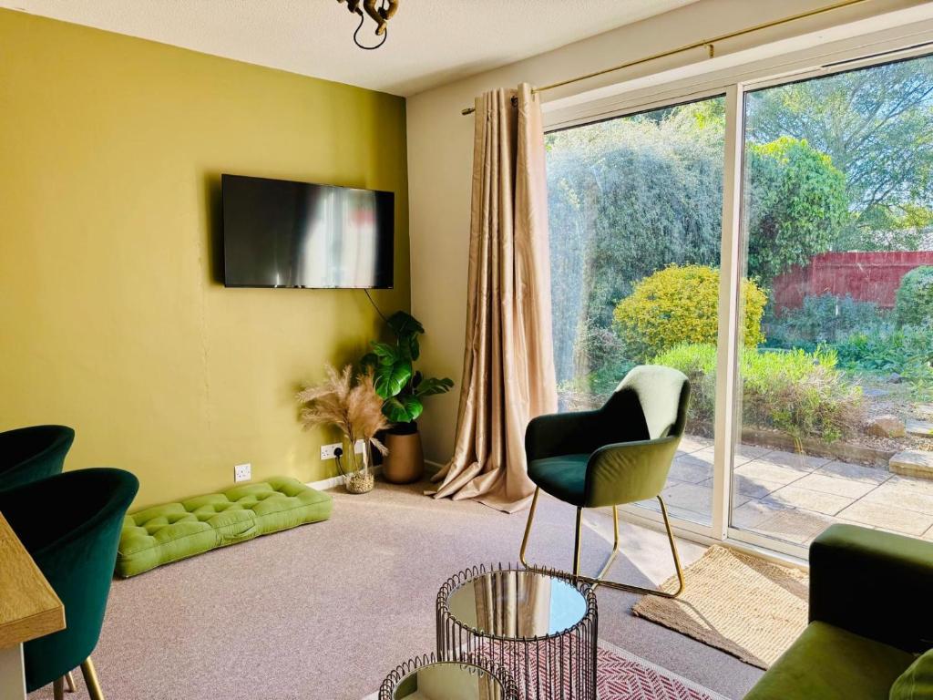 ein Wohnzimmer mit einer Couch und einem Fernseher an der Wand in der Unterkunft The Jade House - Cambridge Rental with Garden and BBQ, Near City Centre in Cambridge