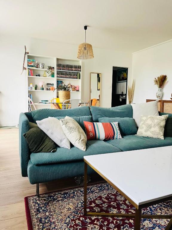 un salon avec un canapé bleu avec des oreillers dans l'établissement Au Point Carré - Appartement tout confort au calme, à Bordeaux