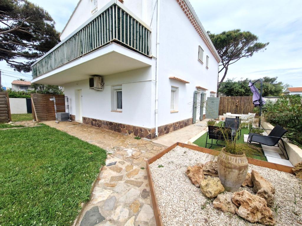 Elle offre une vue sur une maison blanche dotée d'un jardin. dans l'établissement 2 pièces en rez-de-villa avec beau jardin près plage, à Hyères