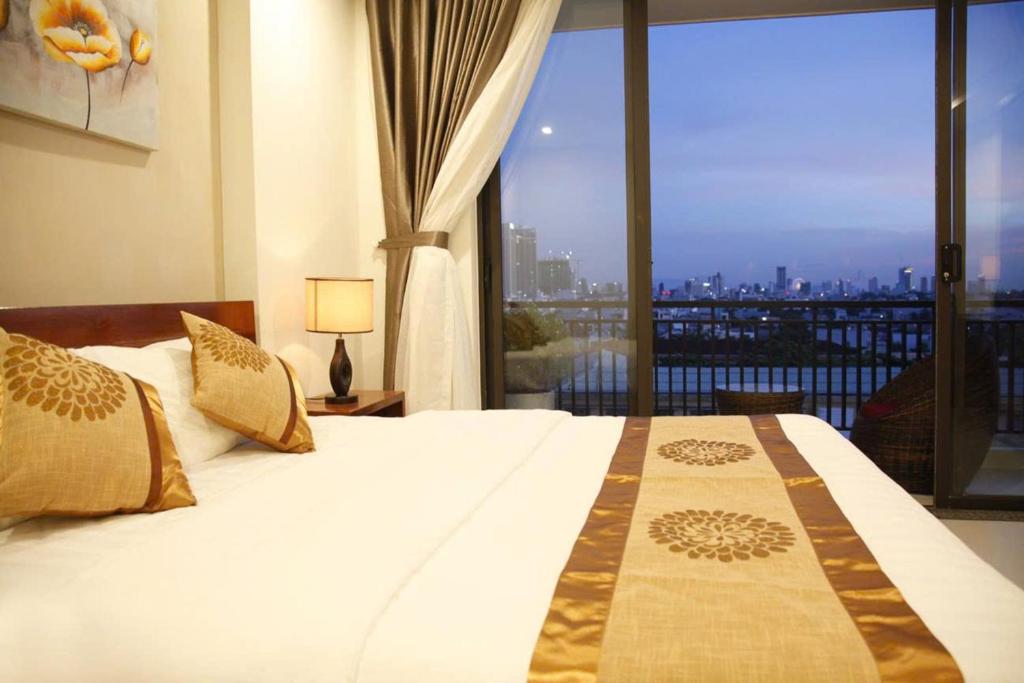 een slaapkamer met een bed en een groot raam bij Son Tra Green Hotel & Apartment in Da Nang
