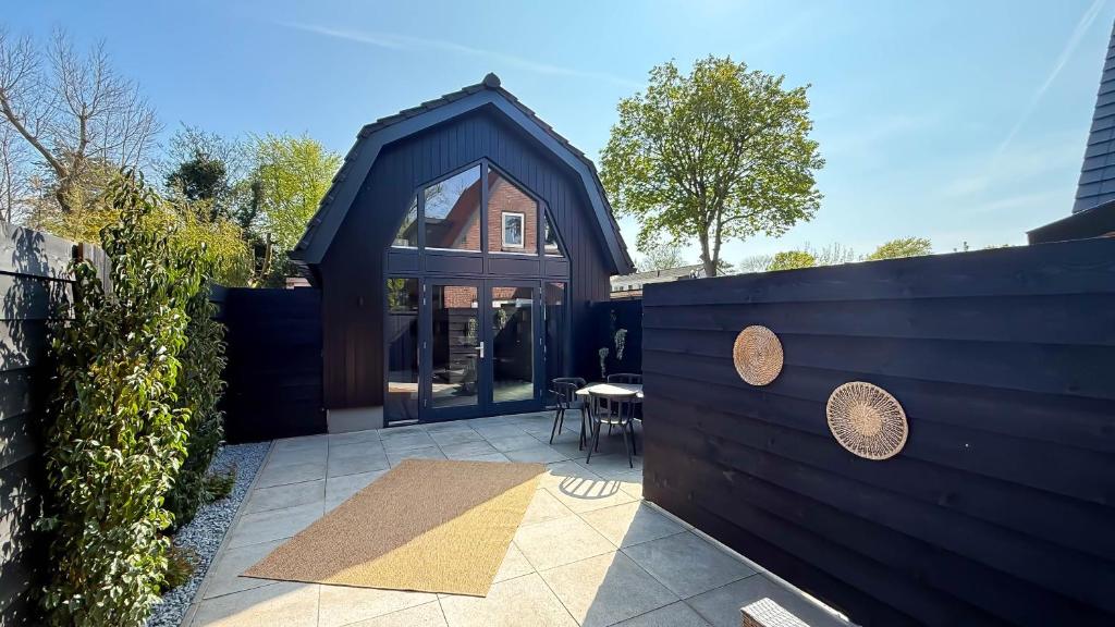 a house with a black wall and a patio at 't Boschhuys by Droomvilla in Bergen