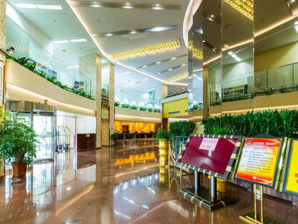 a building with a lobby with plants in it at The Twenty First Century Hotel in Beijing