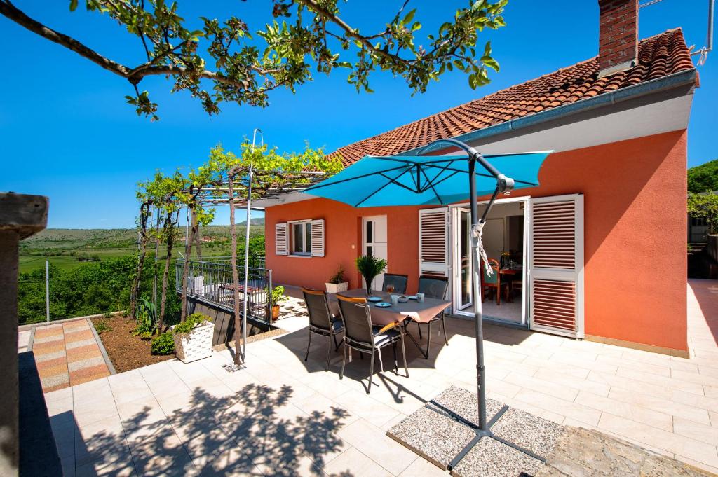 a patio with a table and an umbrella at House MM in Čavoglave