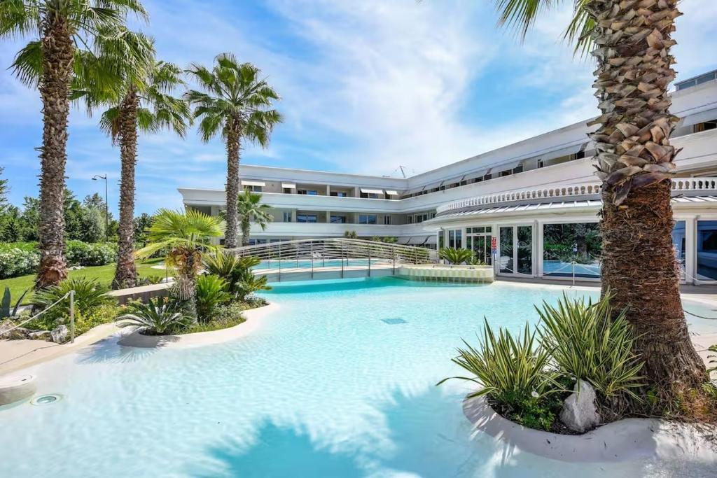 een zwembad voor een gebouw met palmbomen bij Casa Royale al Relais Du Lac in Desenzano del Garda