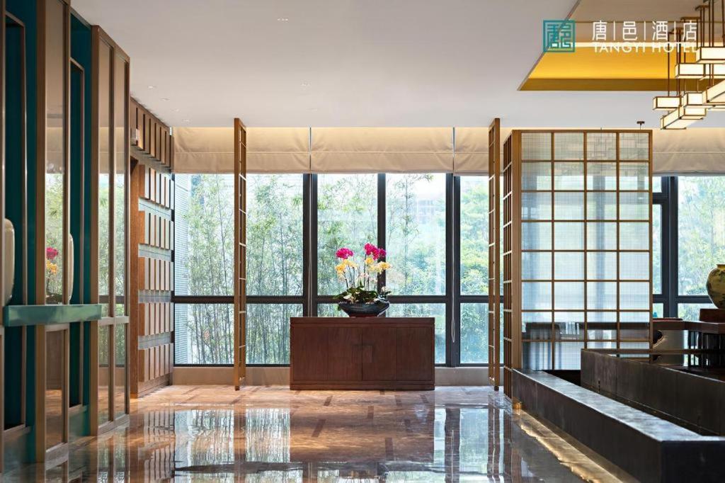 Una habitación grande con ventanas y un jarrón de flores. en Zhuhai Tangyi Hotel, en Tongka