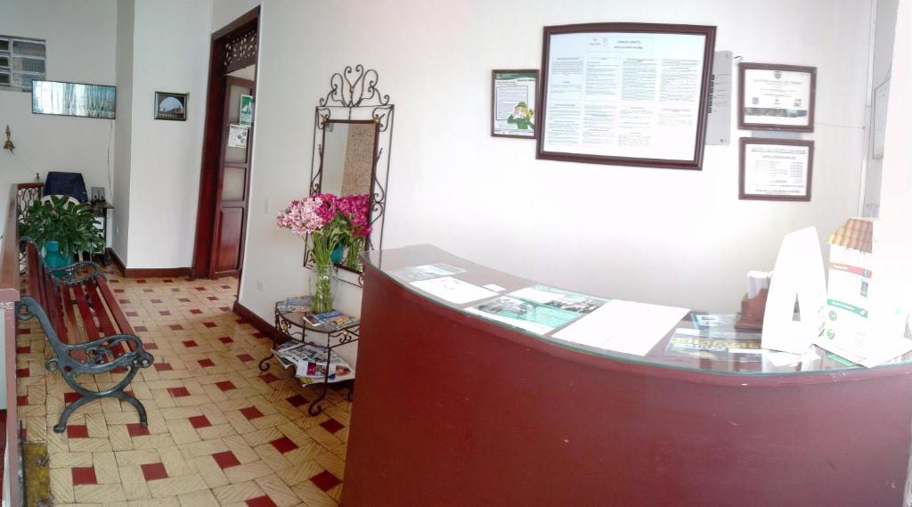 a lobby with a counter and a mirror and flowers at Hotel Alcayata Colonial in Popayan