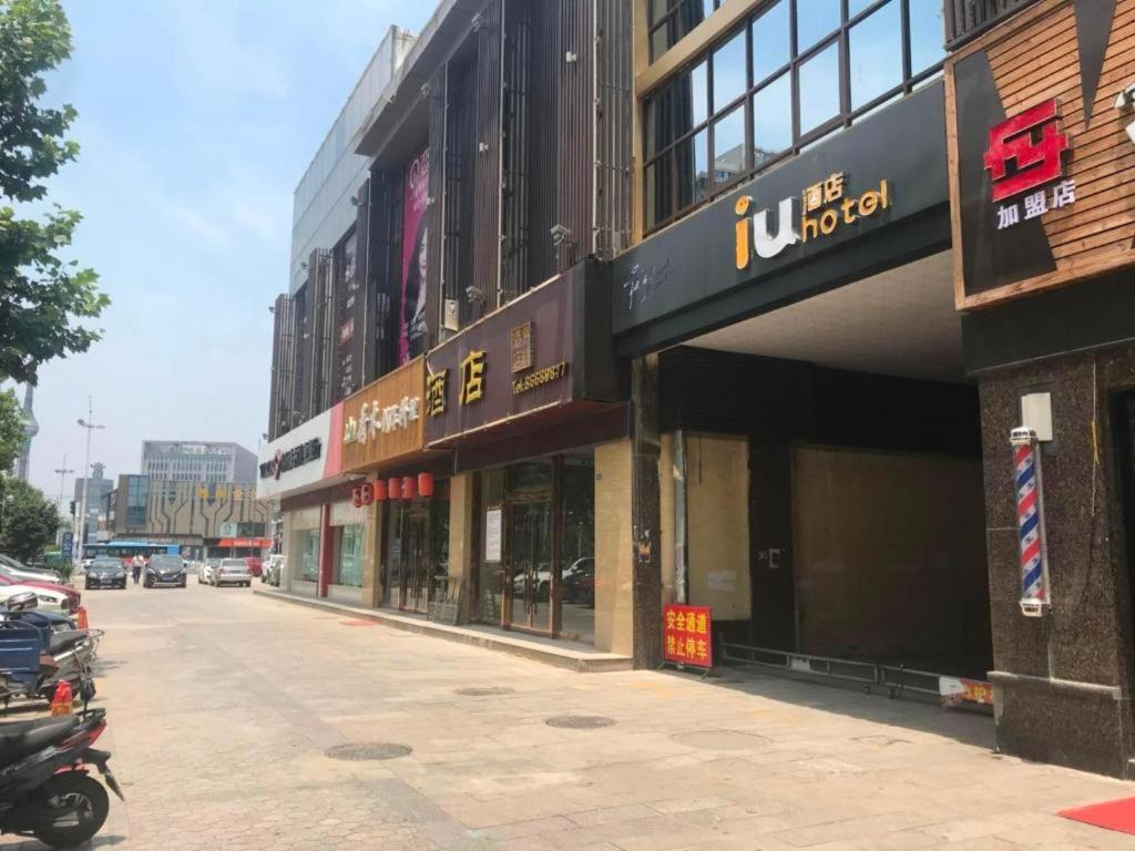 a row of buildings on a street with a motorcycle parked outside at IU Hotel Taizhou Wanda Plaza in Taizhou